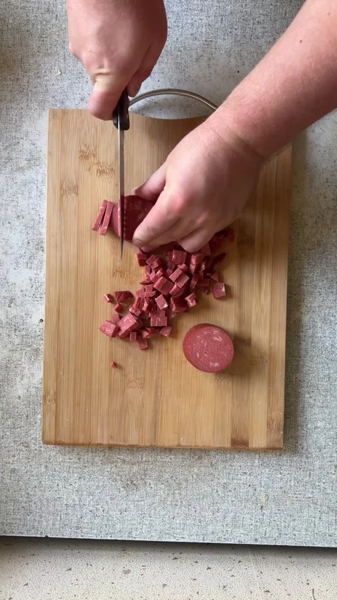 Vertical 4K video. Man cuts with knife on wooden chopping board on kitchen table Stock Footage 277236657
