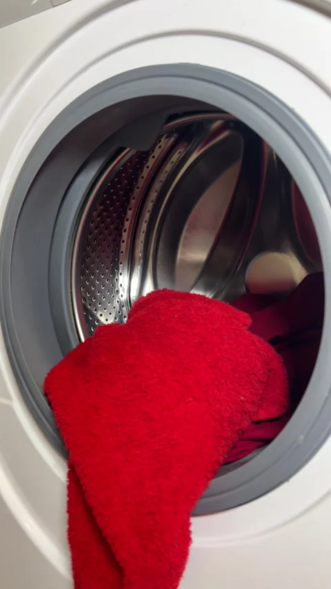 Vertical 4K video. Man puts clothes into washing machine Stock Footage 314505109