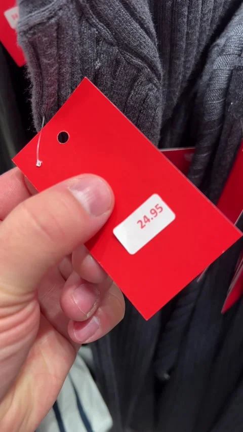 Vertical 4K video. Man turns over red price tag on clothes. Number 24.95 Video stock 308562490
