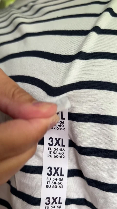 Vertical 4K video. Man in white T-shirt with stripes removes 3XL sticker Vídeos de archivo 316356778