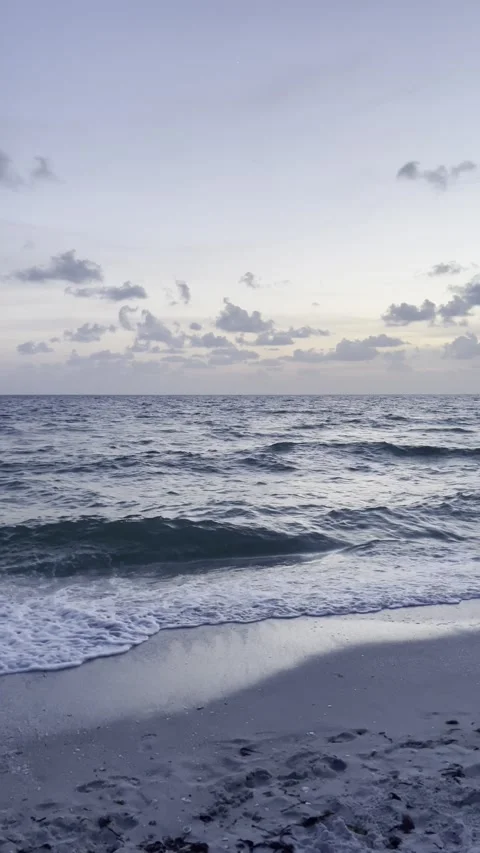 Vertical 4K video of ocean waves at sunset beneath a deep blue sky Stock Footage 342080024