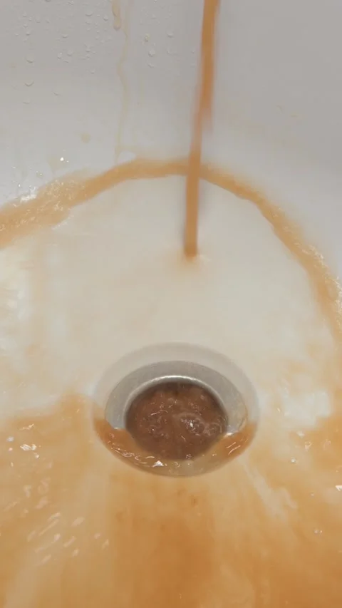 Vertical 4K video shows rusty tap water flooding bathtub drain, exposing failing Stock Footage 315127742