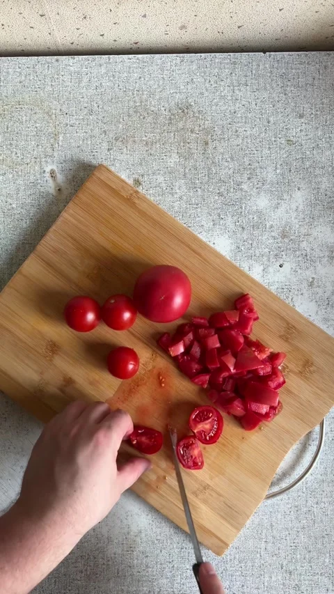 Vertical 4K video. Top view. Man cuts red fresh juicy tomatoes with knife Stock Footage 277756059