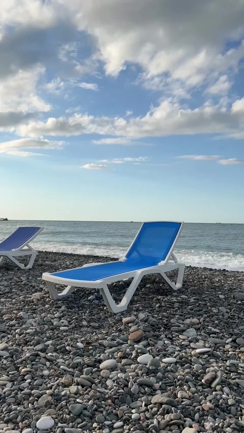 Vertical 4K video. View of blue and white sun lounger on shore line on beach Stock Footage 271168773