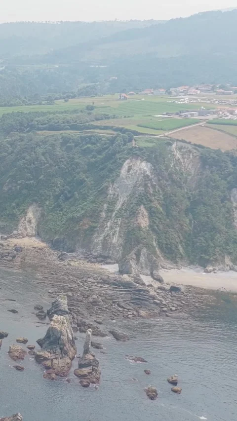 Vertical 9:16 aerial video showcasing the dramatic rocky coastline and steep Stock Footage 346662601