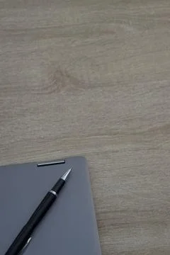 Vertical 9:16 composition of laptop corner and pen on wood with negative spac Stock Photos