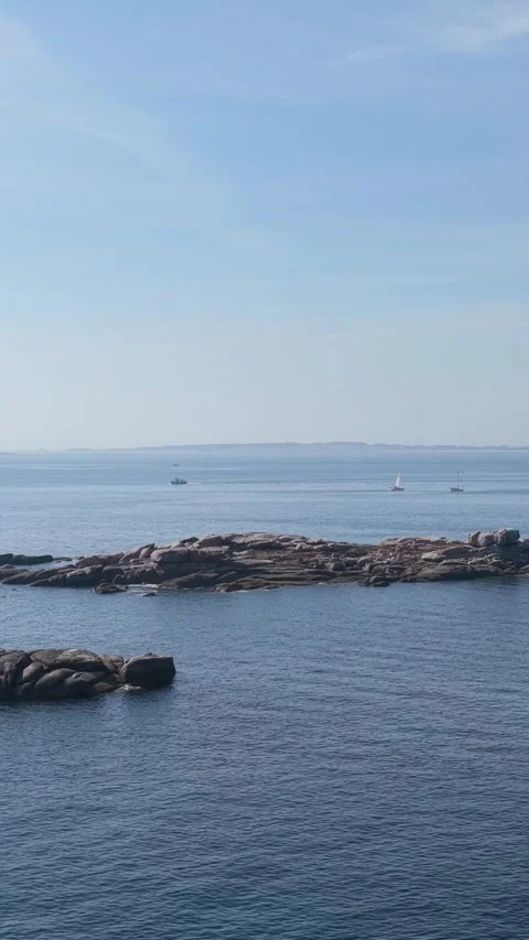 Vertical 9:16 video capturing the rocky shoreline and calm blue waters at Praia Stock Footage 346663624