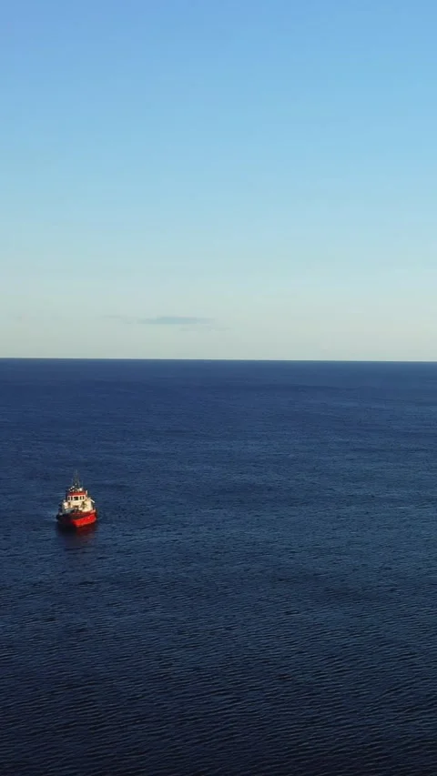 A vertical 9:16 video showing a red and white boat moving across the calm blue Stock Footage 346663054