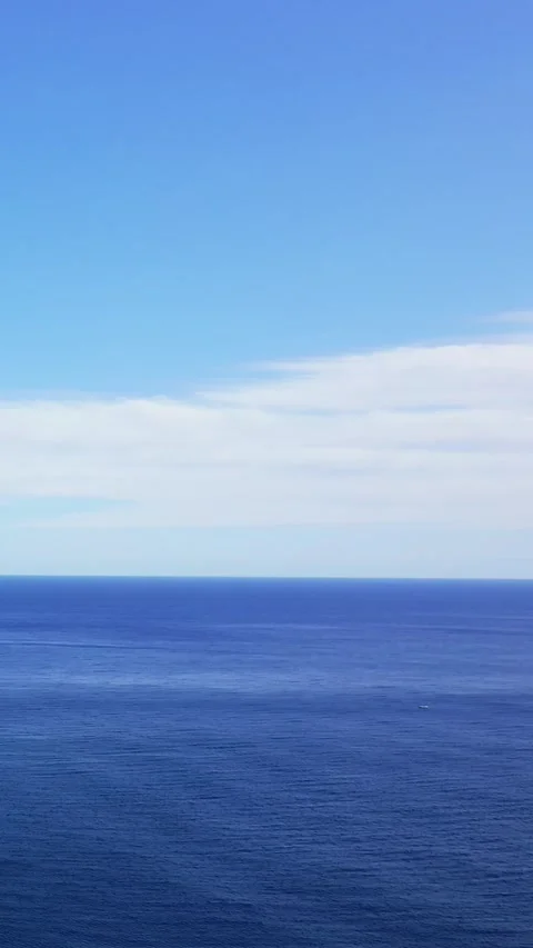 Vertical 9:16 video showing a wide expanse of deep blue sea meeting a clear sky Stock Footage 346662852