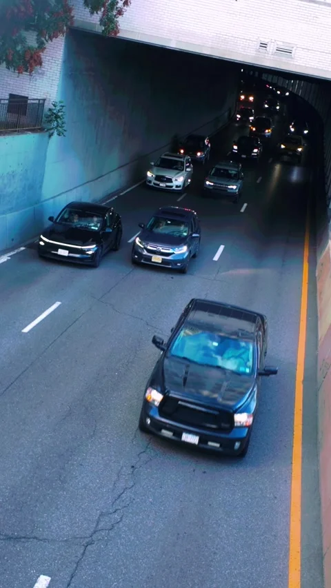 Vertical 9:16 view of cars emerging from a dark city tunnel underpass. Stock Footage 345174871