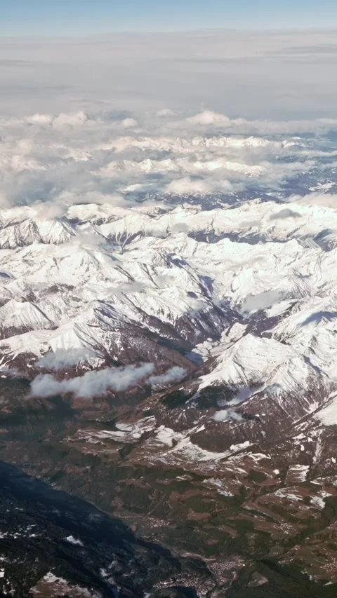 Vertical Above peaks a clouds covers sky, snow capped Alps rugged mountain peaks Stock Footage 313007899
