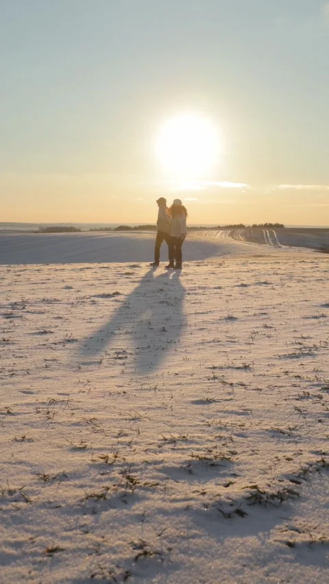 Vertical. Active married couple walks in snowy meadow in cold winter evening on Vídeos de archivo 328979591