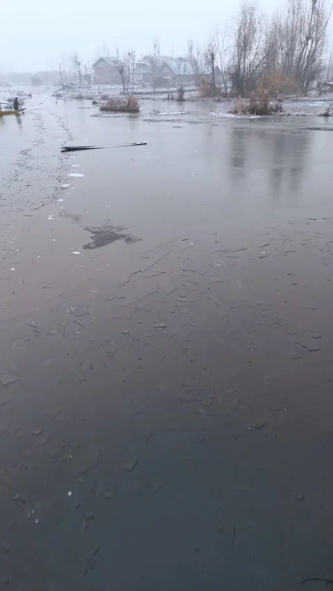 Vertical Aerial drone gaze into the winter freeze blanketing Dal Lake’s daily Stock Footage 311019683