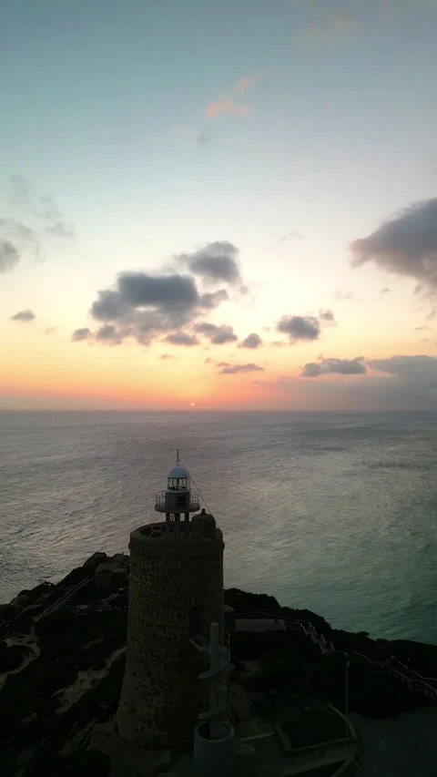 Vertical Aerial drone view approaching lighthouse on sea cliffs at sunset Stock Footage 293064153