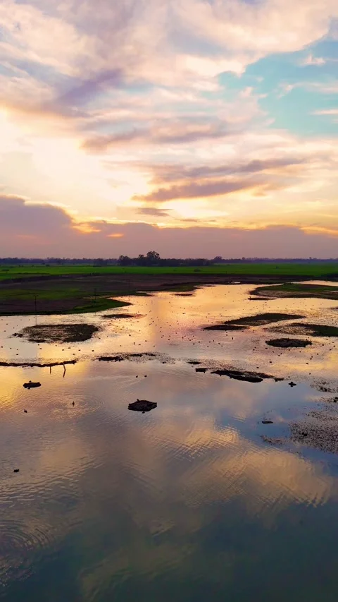 Vertical Aerial drone view capturing warm sunset colors mirrored in still water. 動画素材 310936672