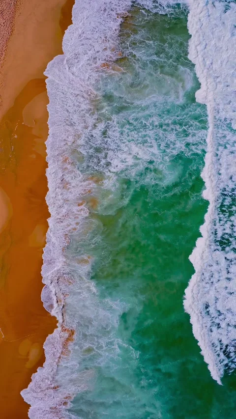 Vertical aerial drone view of ocean waves crashing on sandy beach Stock Footage 345100893