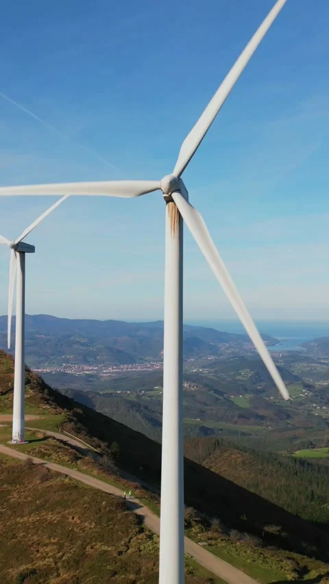 Vertical aerial drone view of wind turbine rotating with green valley and b.. Stock Footage 294976149