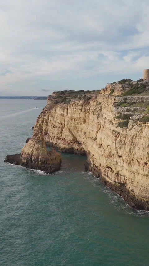Vertical Aerial Flight Along Ferragudo's Golden Coastline and Torre da Lapa 動画素材 347123748