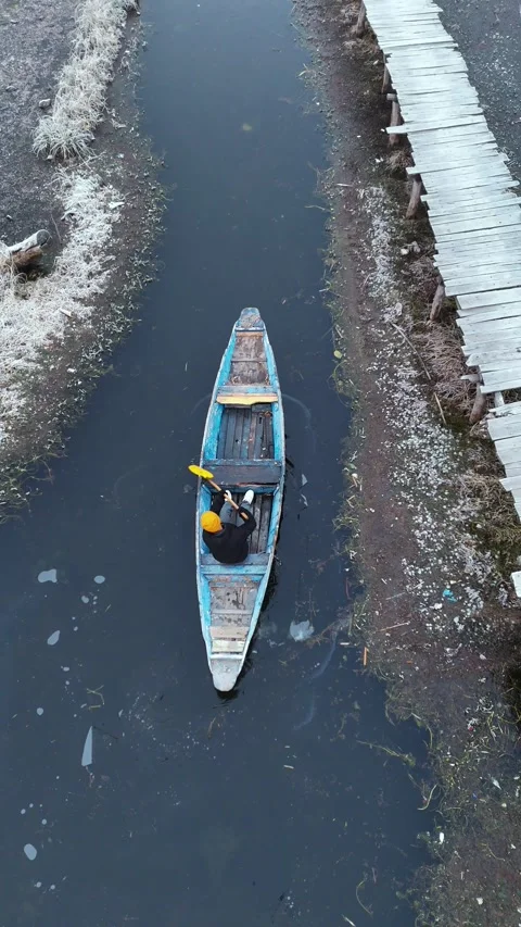 Vertical aerial frame of a boatman clearing snow to navigate the frozen Dal Stock Footage 311019909