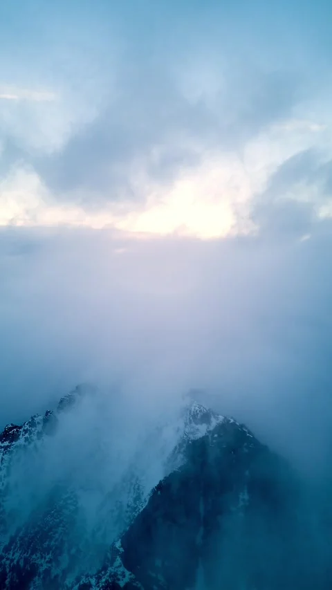 Vertical aerial hyperlapse of clouds moving over snowy mountain peak Stock-Footage 327594085