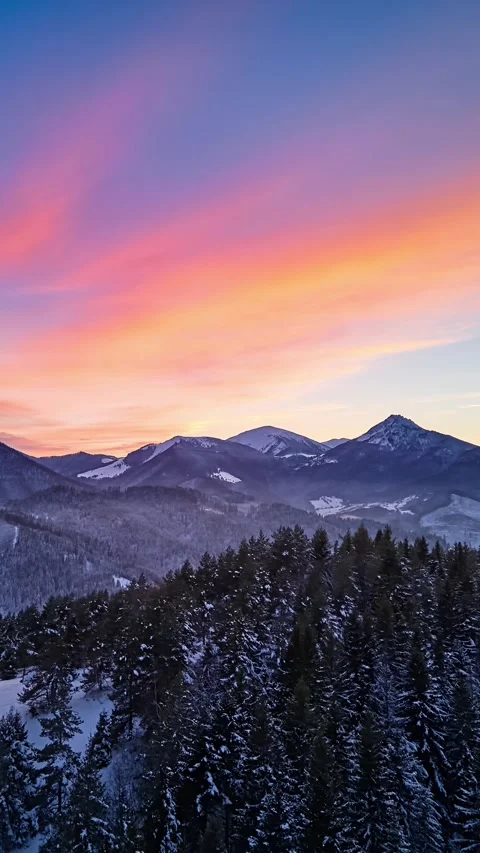Vertical Aerial hyperlapse over winter mountain forest and snowy peaks under Stock Footage 323216709