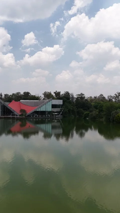 Vertical aerial panning view over Lago Mayor with modern pavilion reflection Stock Footage 342331223