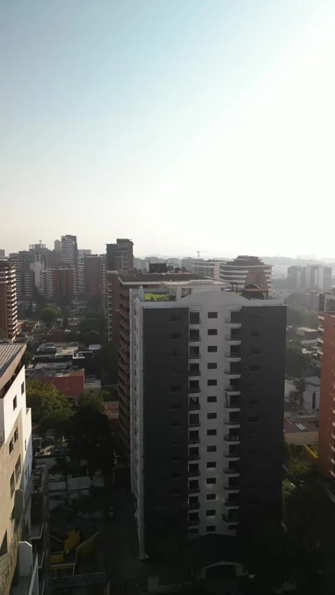 Vertical aerial pull away from skyscraper in downtown Guatemala City smoggy sky Stock Footage 329455506