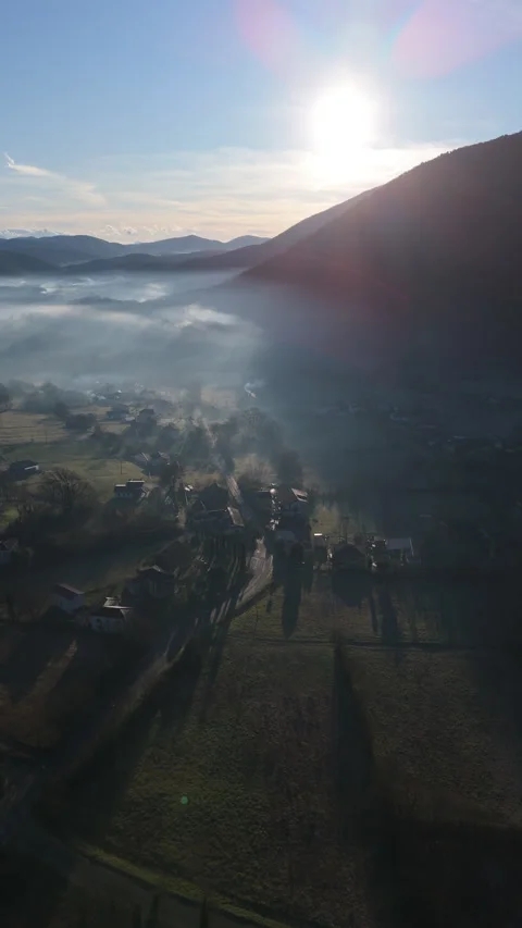 Vertical aerial of sun glowing through morning mist over an Italian valley Video stock 328124373