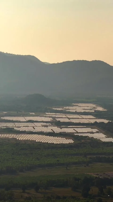 Vertical Aerial Sunset View of Mountain Valley with Reflective Solar Panels in Stock Footage 318461997