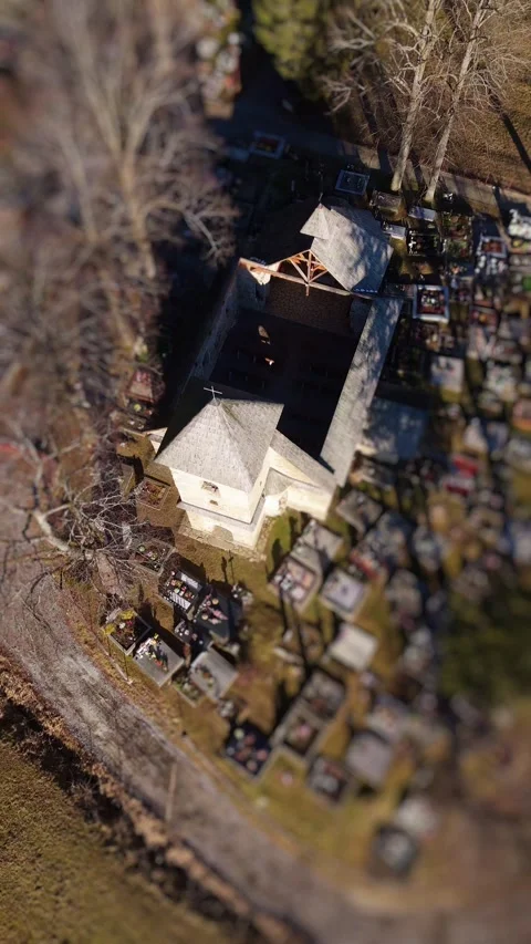 Vertical Aerial Tilt-Shift View of an Old Church in the Middle of a Cemetery in Stock Footage 296577793