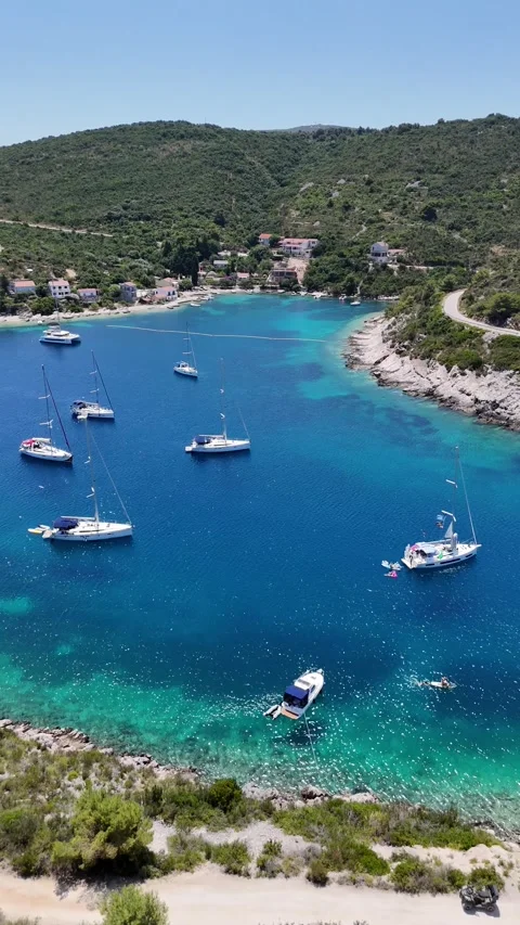 Vertical aerial view of anchored sailboats in a clear turquoise cove. Stock Footage 327677053