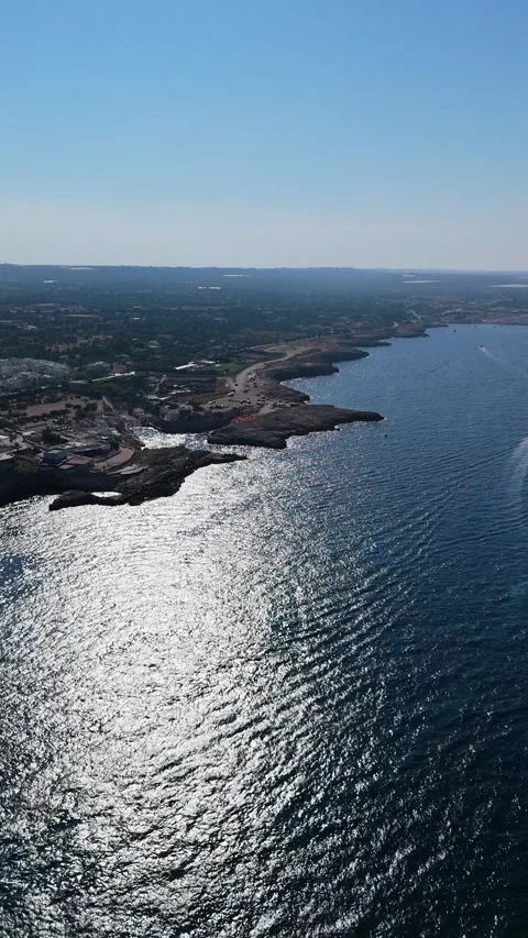 Vertical aerial view of bright sun glitter spreading across dark blue sea along Stock-Footage 346098697