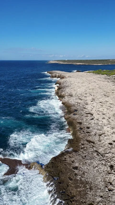 Vertical aerial view of clear turquoise water hitting a rocky coastline. Stock Footage 327672915
