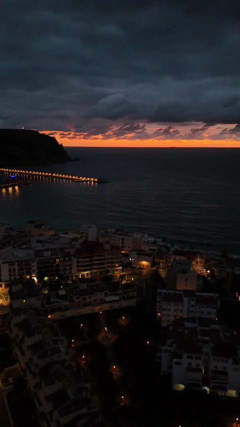 Vertical aerial view of curved beach and lit pier at dusk, Javea, Spain Stock Footage 339989886