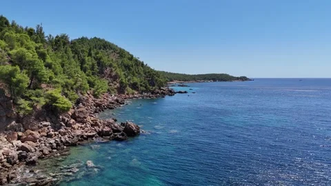 Vertical aerial view of deep blue water and a rugged Greek shoreline. Video stock 327674793