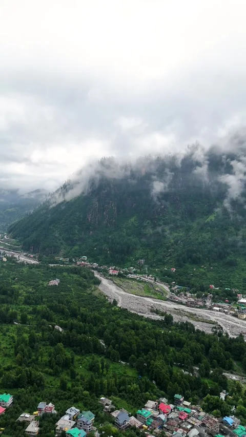 Vertical aerial view of drone moving out of the clouds and revealing a himalayan Stock Footage 310659326