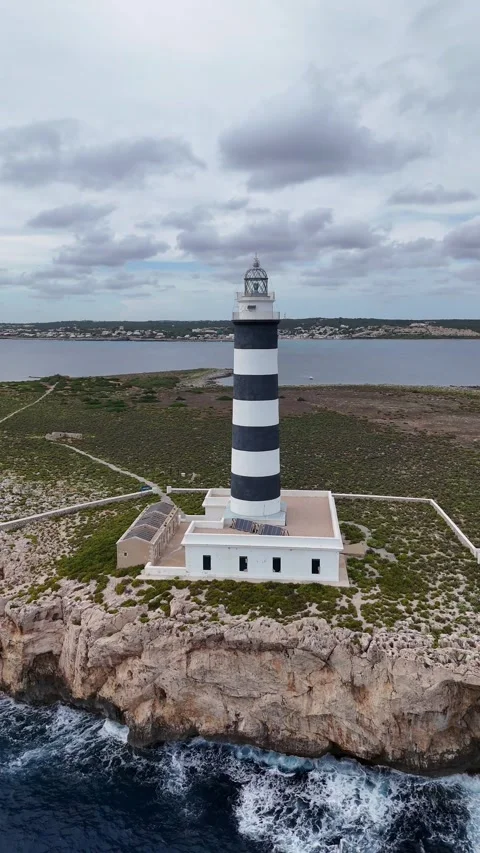 Vertical aerial view of the iconic striped lighthouse on the rocky Illa de Aire Video stock 327670323