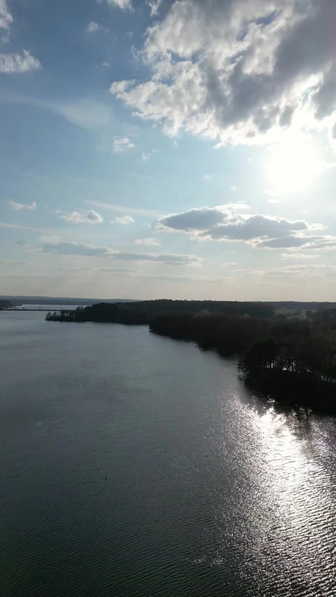 Vertical Aerial View of Lake With Sunlight Reflection and Dramatic Clouds Stock Footage 341095818