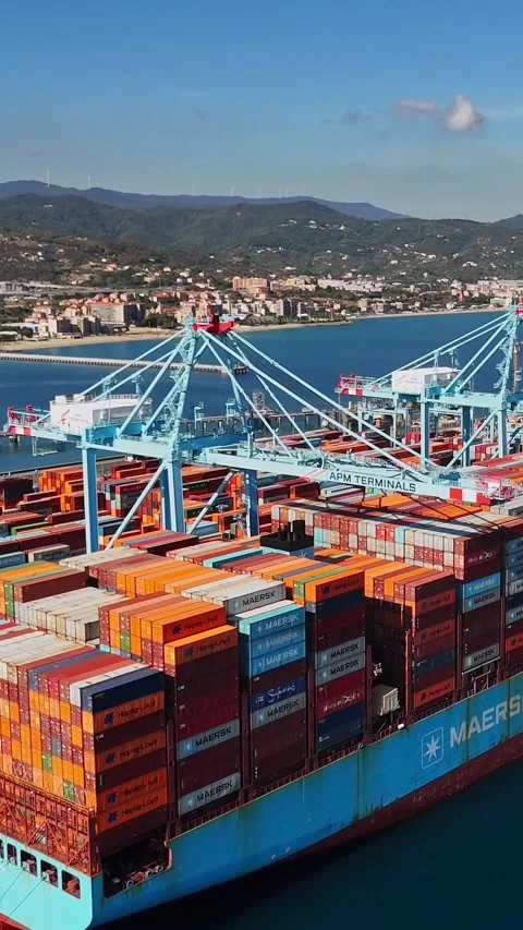 Vertical aerial view of a loaded container ship beside gantry cranes at Vado Stockbeeldmateriaal 347844712