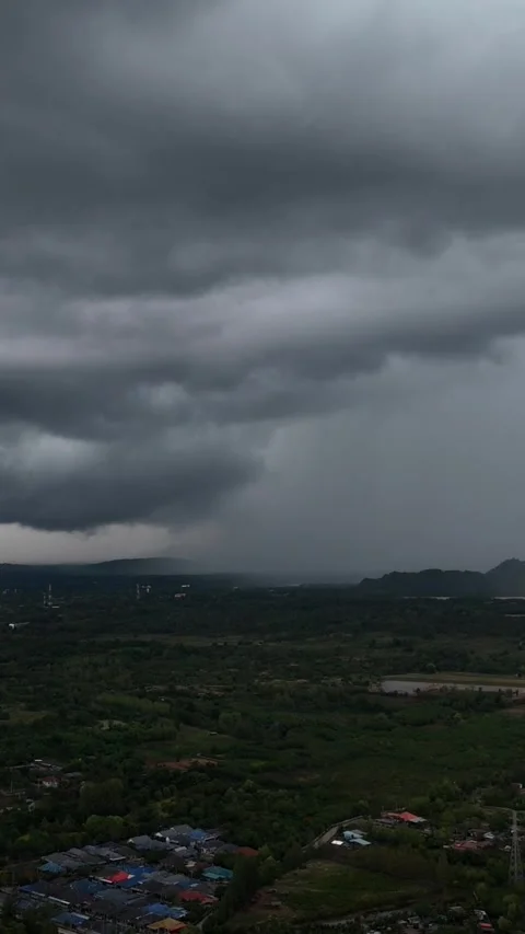 Vertical aerial view of Massive storm cloud releases rain over forested valley Stock Footage 314931474