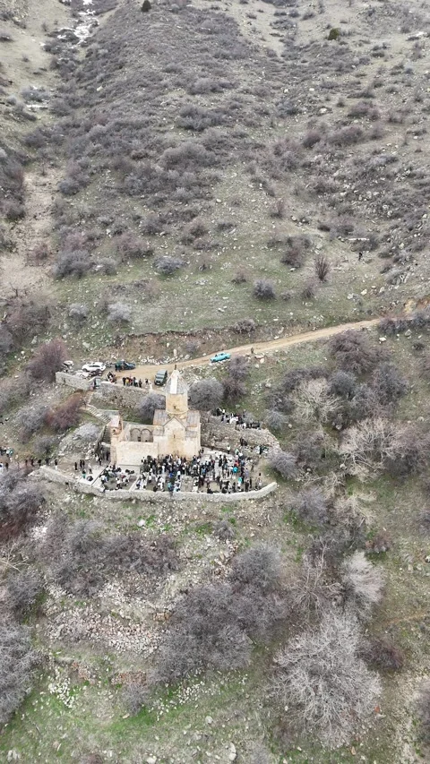 Vertical aerial view of medieval mountain church surrounded by hikers. Vídeo Stock 333925667