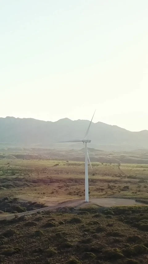 Vertical aerial view of one wind turbine rotates against mountains at sunset Stock Footage 296631208
