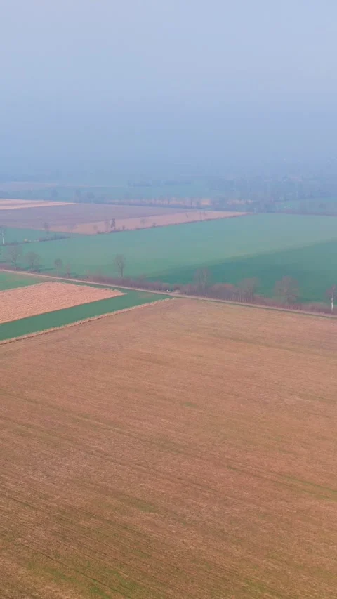 Vertical aerial view of patchwork agricultural fields in a misty rural land 스톡 동영상 332022166