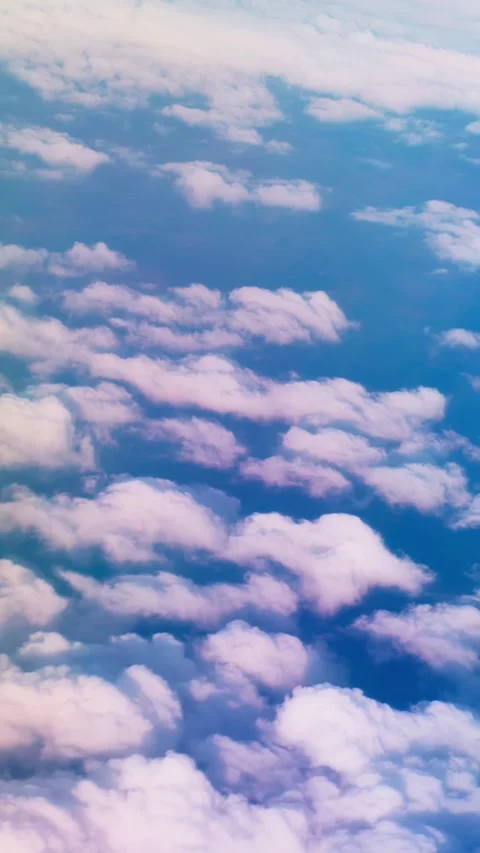 Vertical aerial view of soft white clouds drifting through a blue sky, creating Видео 335276979