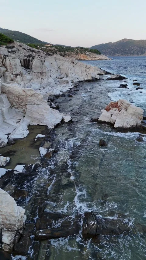 Vertical aerial view of the sun setting over white marble coastal rocks. Stock Footage 327674676