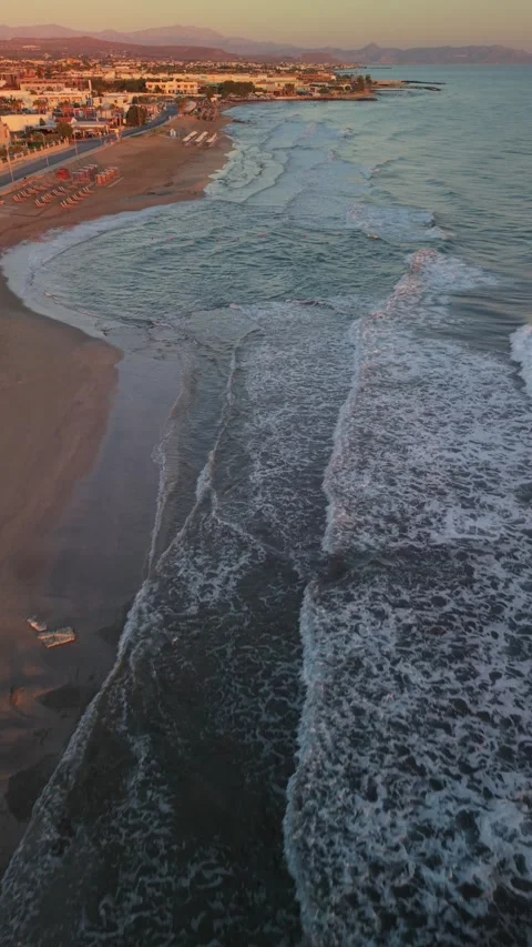 Vertical aerial view of waves washing sandy beach at sunrise in Crete Greece Stock Footage 337404222