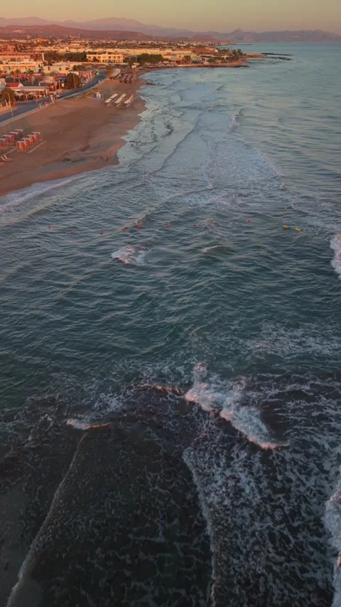 Vertical aerial view of waves washing sandy beach shoreline at sunrise in Crete Stock Footage 337405015