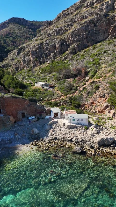 Vertical aerial view of whitewashed cottage in rocky cove, Cala Llebeig, Spain Stock Footage 340238975