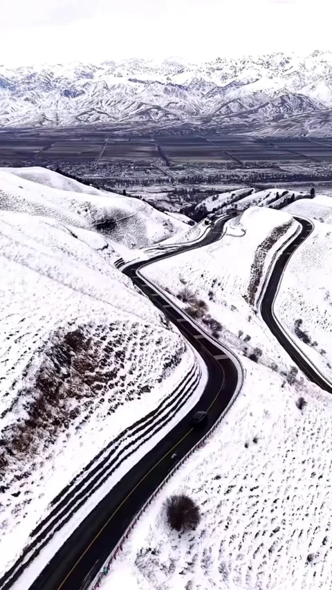 Vertical aerial view of winding road in snow mountains, Xinjiang, China. Stock Footage 328890710