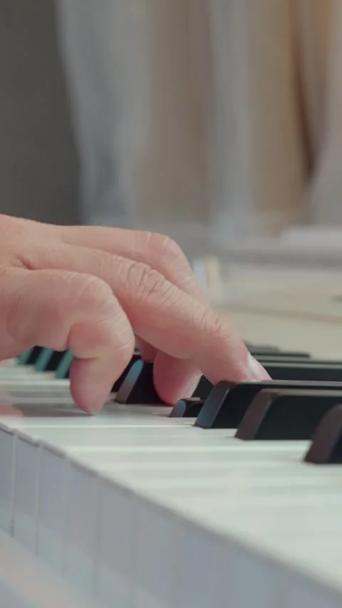 Vertical aesthetic shot of single hand playing smooth melody on white piano Video stock 337929758